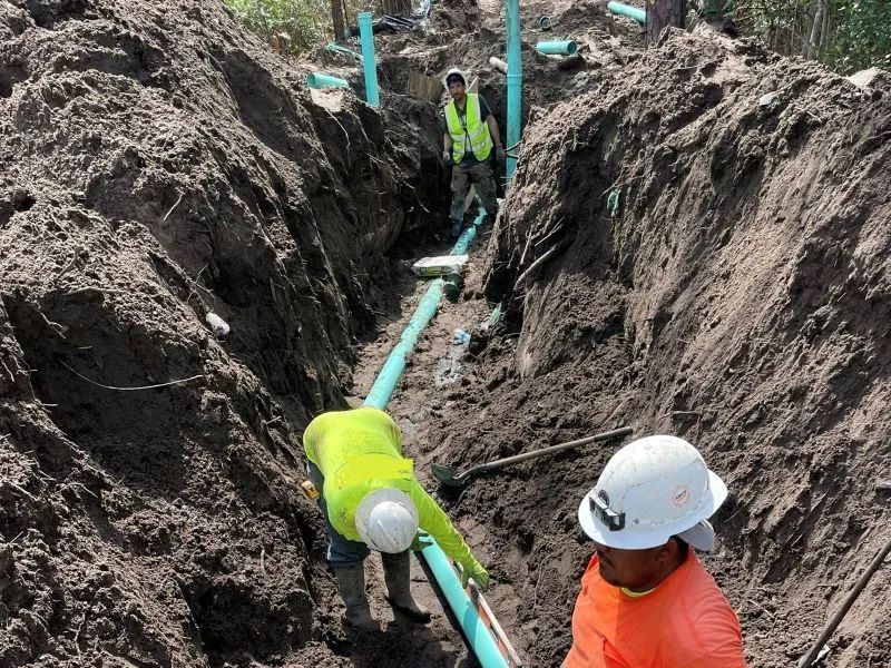 A group of construction workers are working in a trench.
