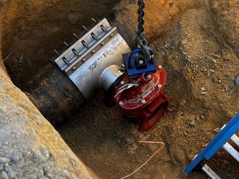 A red pipe is being installed in a hole in the ground.