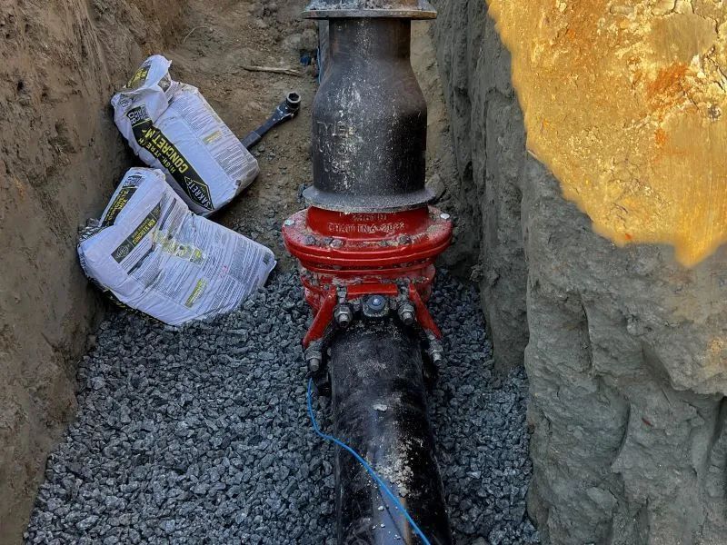 A pipe is being installed in a trench next to a pile of gravel.