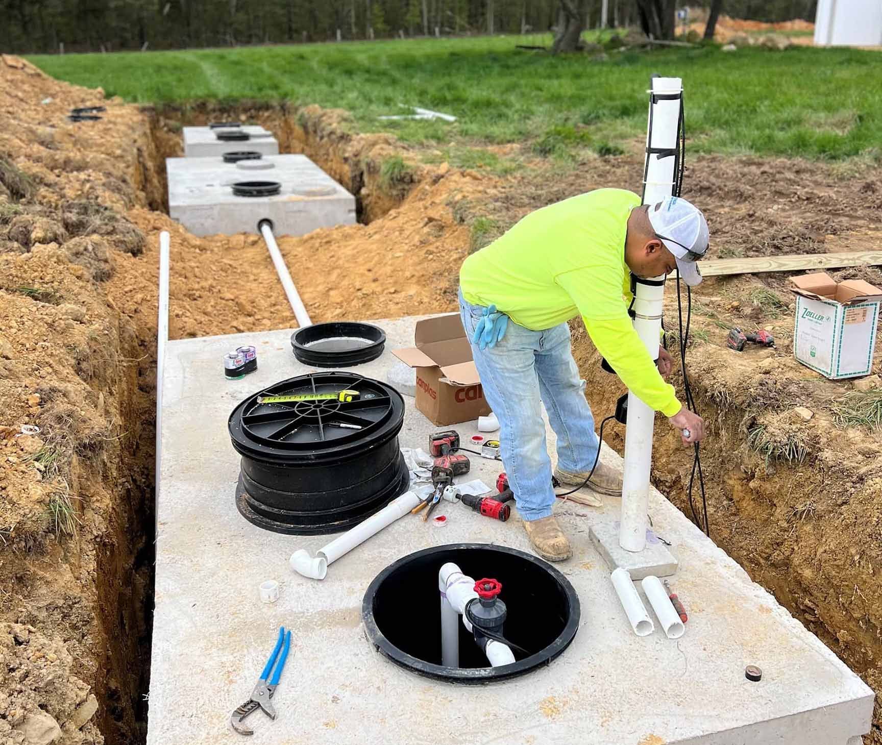 A man is working on a septic tank in the dirt.