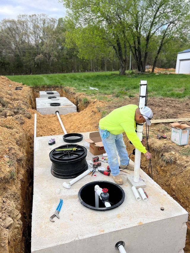 A man is working on a septic tank in the dirt.
