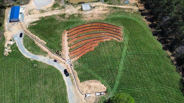 An aerial view of a lush green field with a road going through it.