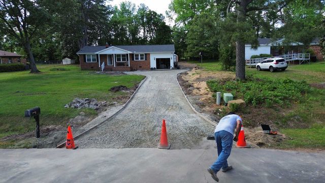 A man is working on a driveway in front of a house.