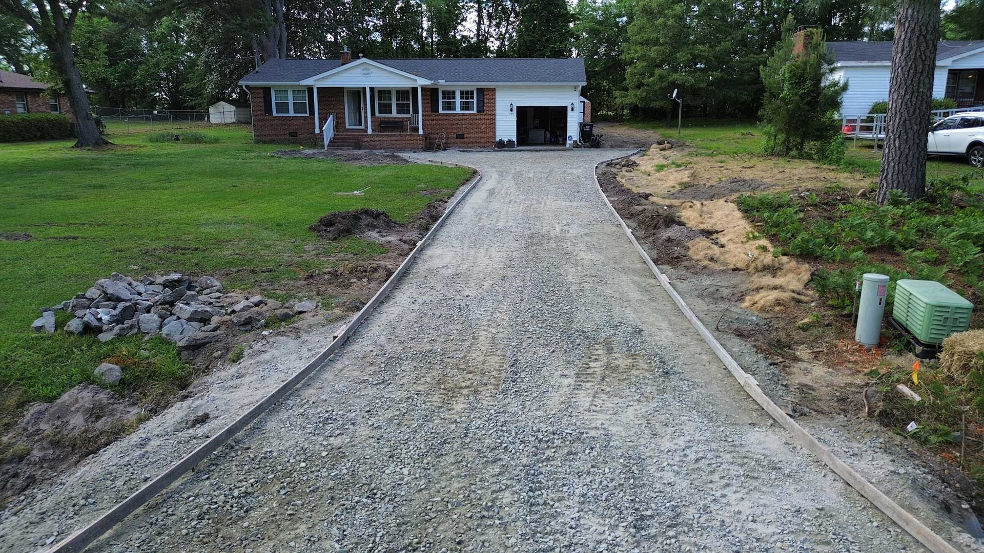 A gravel driveway is being built in front of a house.