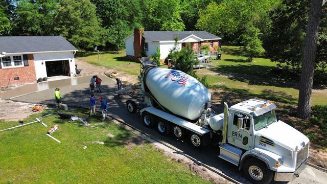 An aerial view of a concrete mixer truck driving down a road in front of a house.