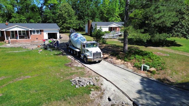 An aerial view of a cement truck driving down a driveway in front of a house.