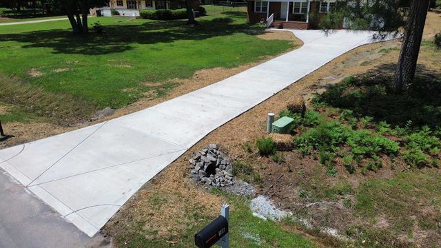 An aerial view of a concrete driveway leading to a house.
