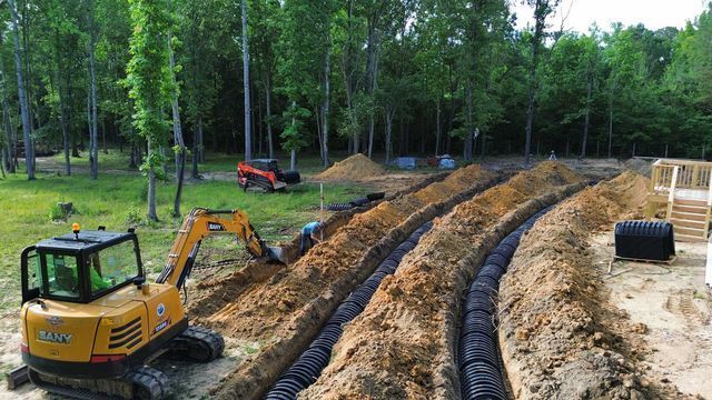 A yellow excavator is digging a trench in the dirt.