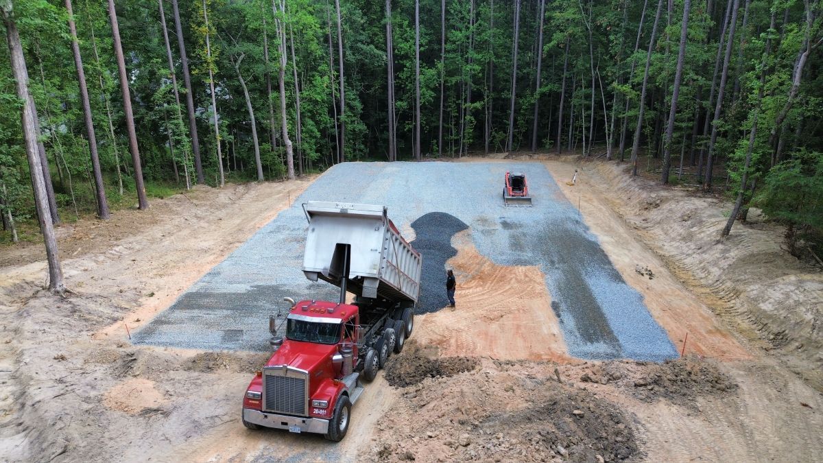 A red dump truck is driving down a dirt road.