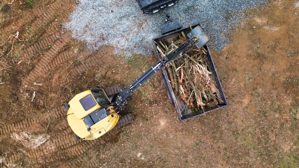 An aerial view of a bulldozer pulling a trailer full of logs.