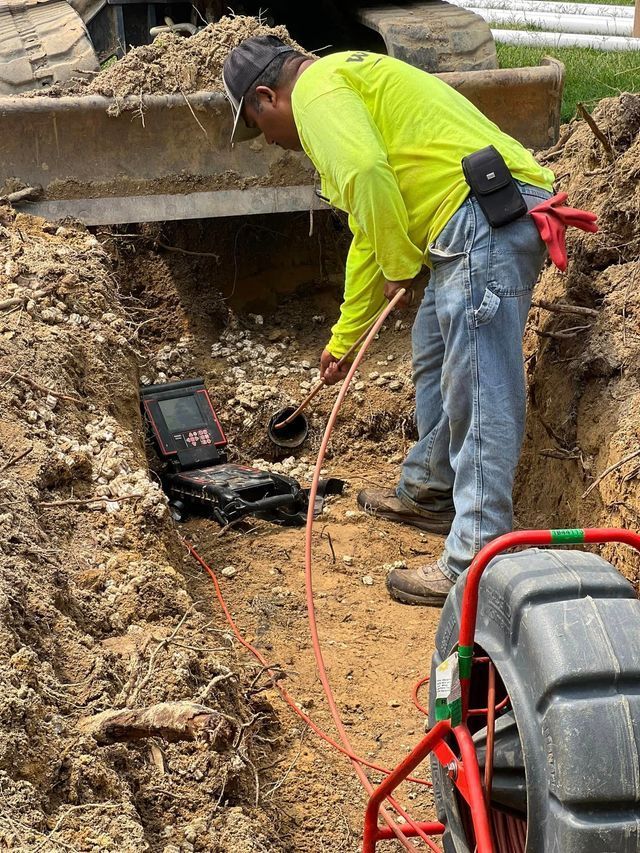 A man is standing in a trench looking at a camera.