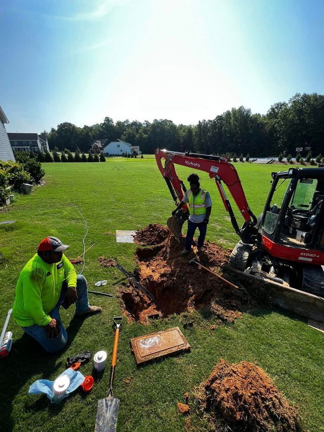 Two men are digging a hole in the grass with a bulldozer.