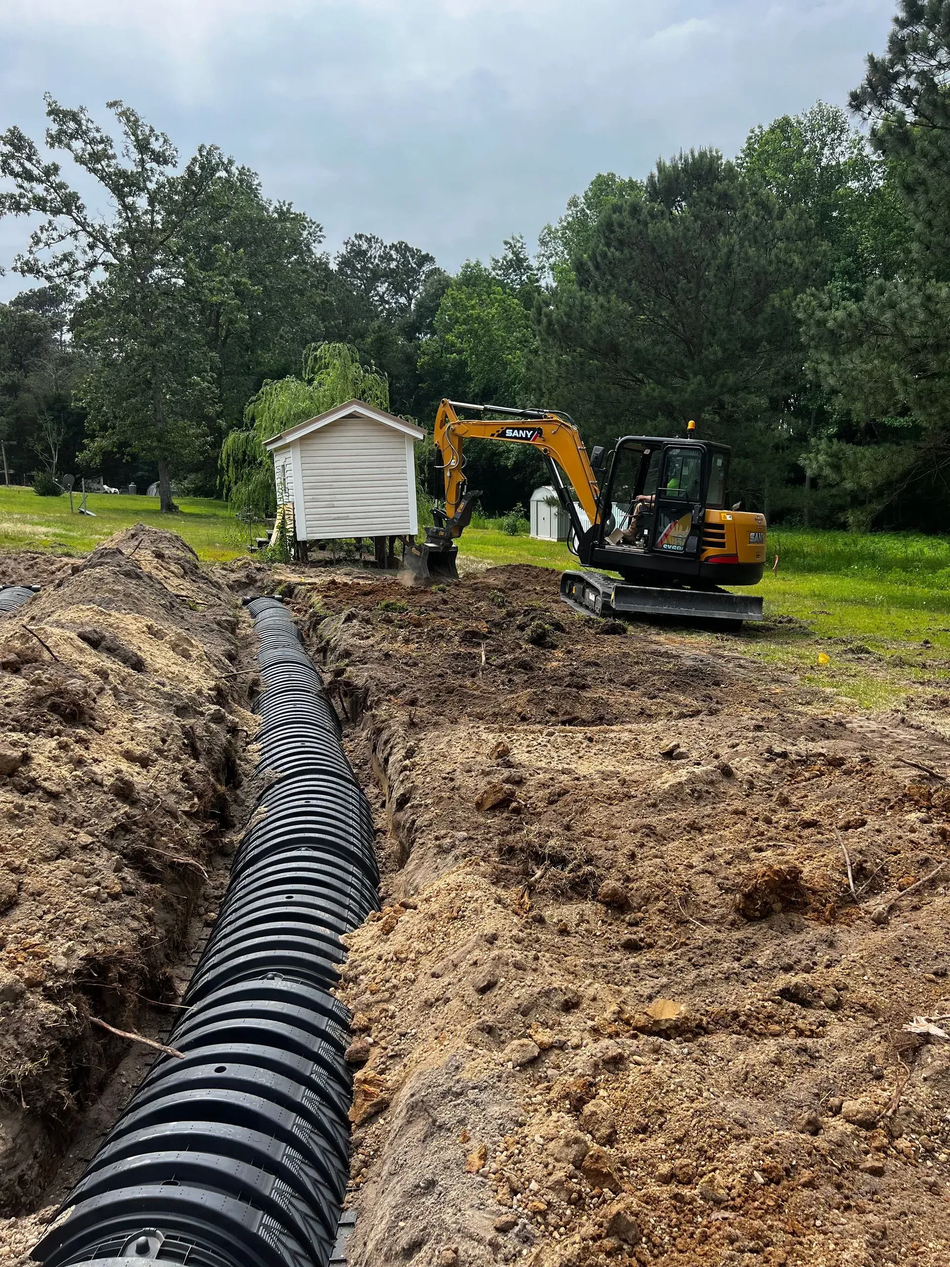 A large black pipe is being installed in a dirt field.