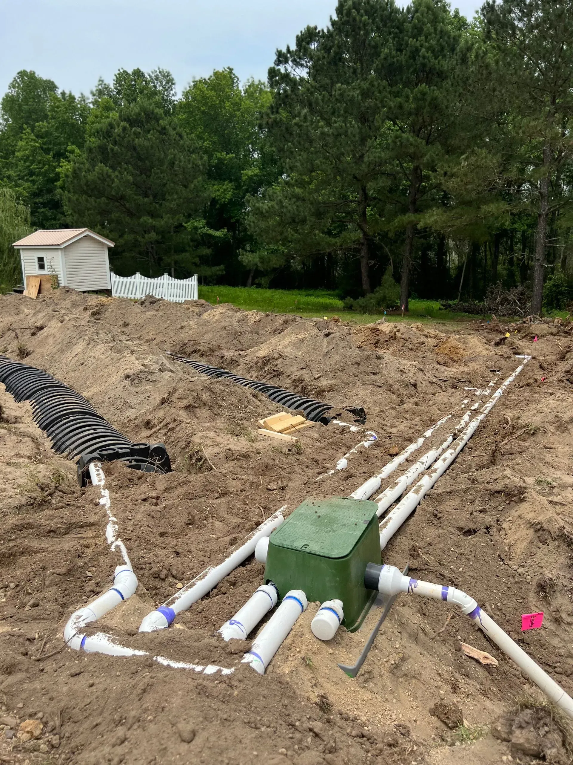 A bunch of pipes are laying in the dirt in a field.
