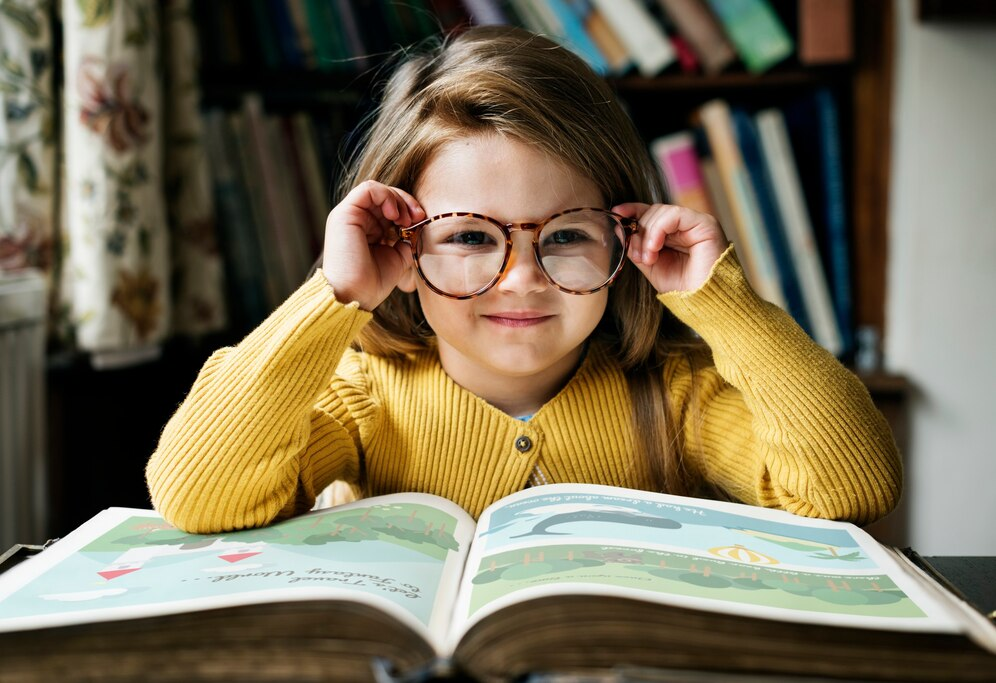 a little girl wearing glasses is reading a book