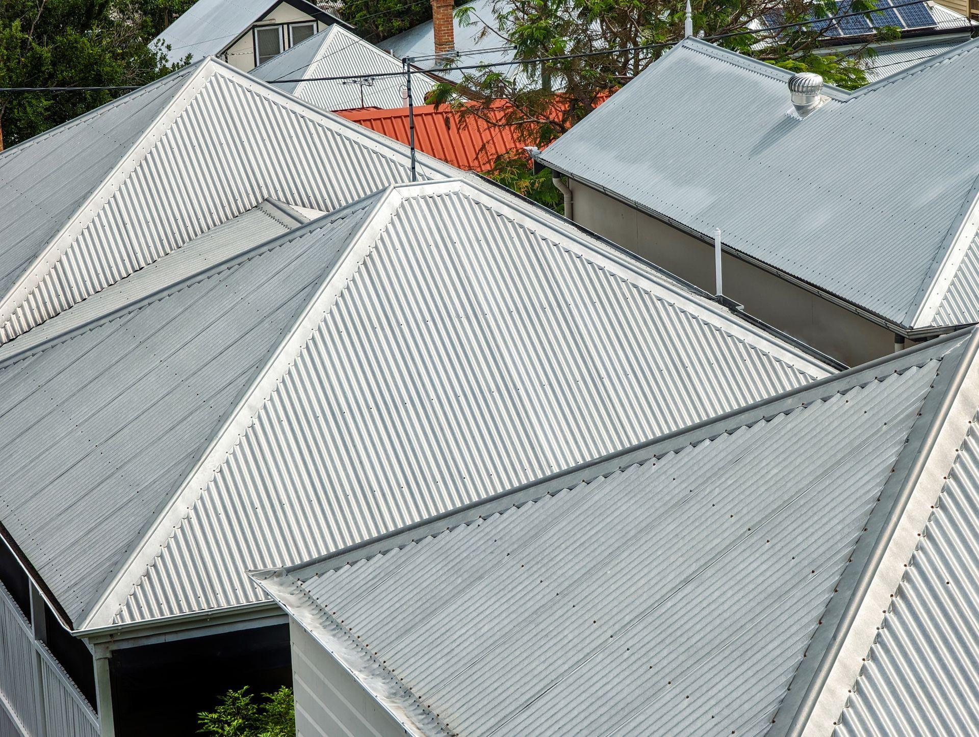 Gray corrugated metal rooftops of several houses, viewed from above.