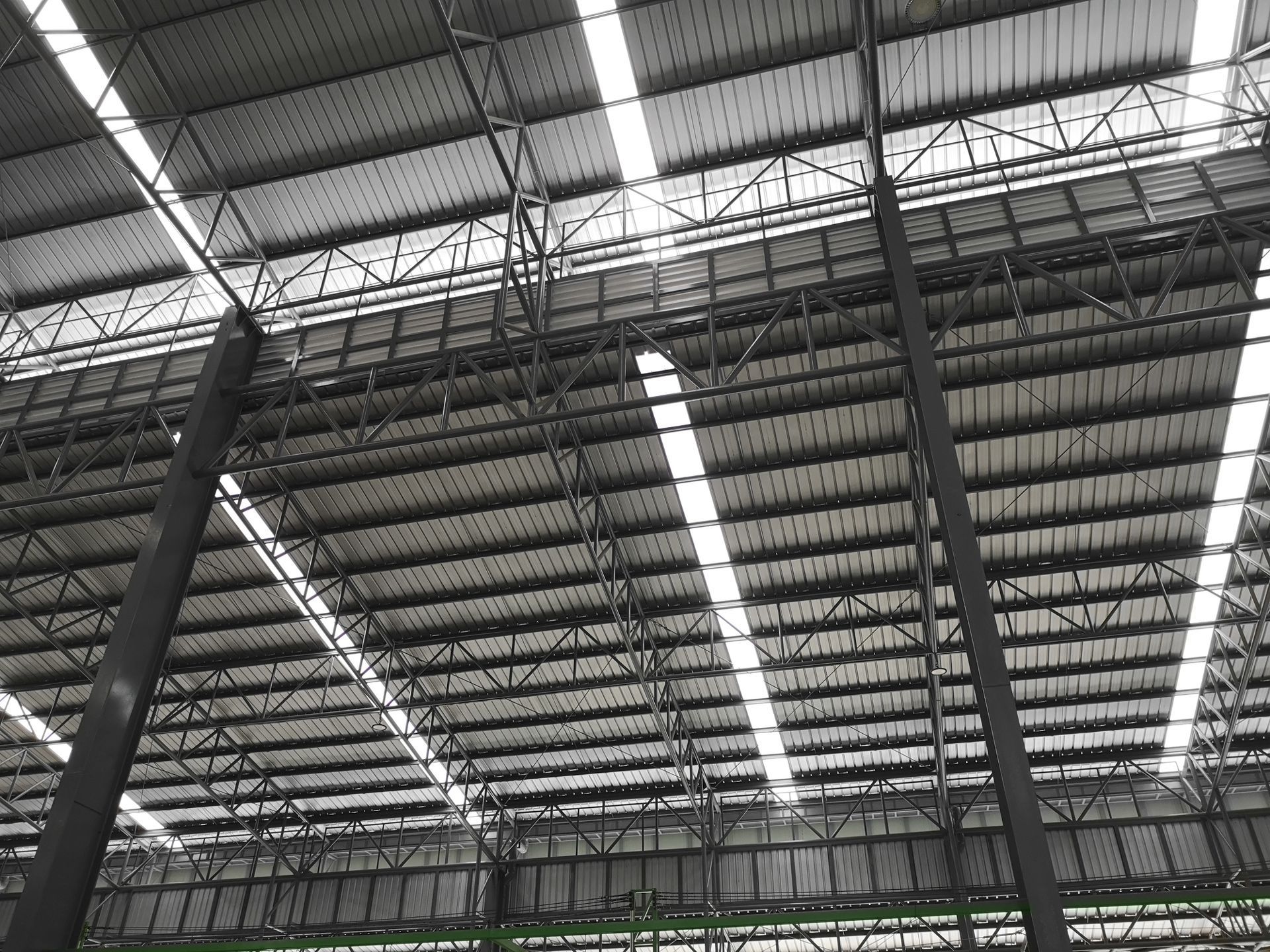 View of a warehouse ceiling with steel beams, metal roofing, and natural light panels.