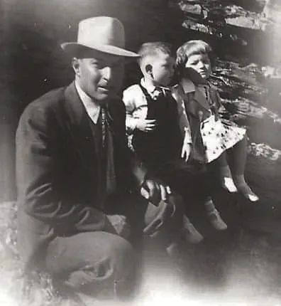 A black and white photo of a man holding two children