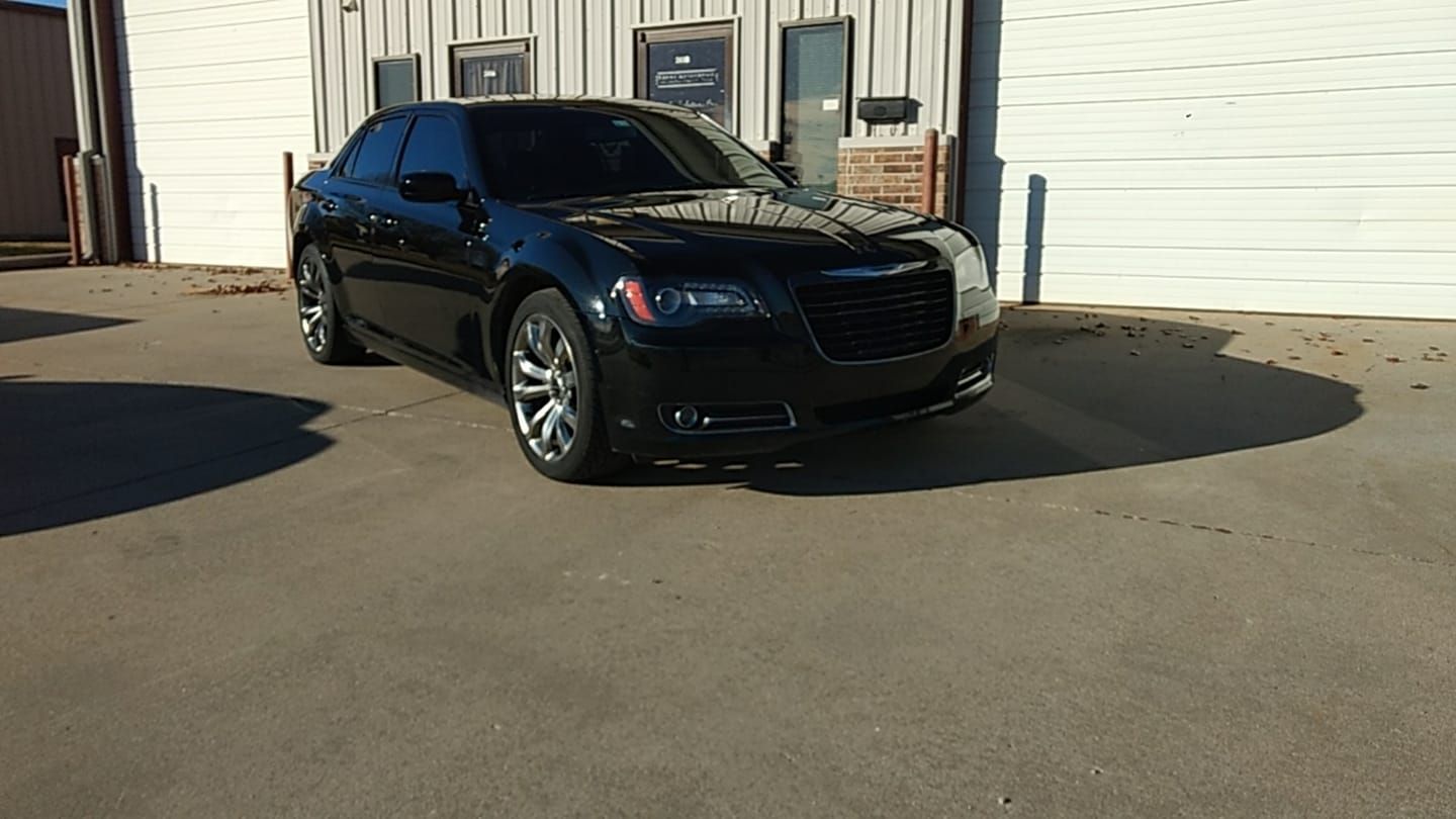 A black car is parked in front of a white garage door.