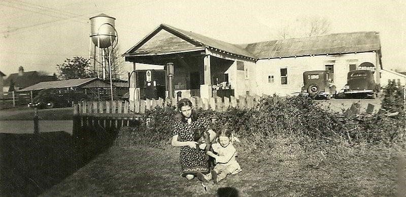 A black and white photo of a house with a water tower in the background