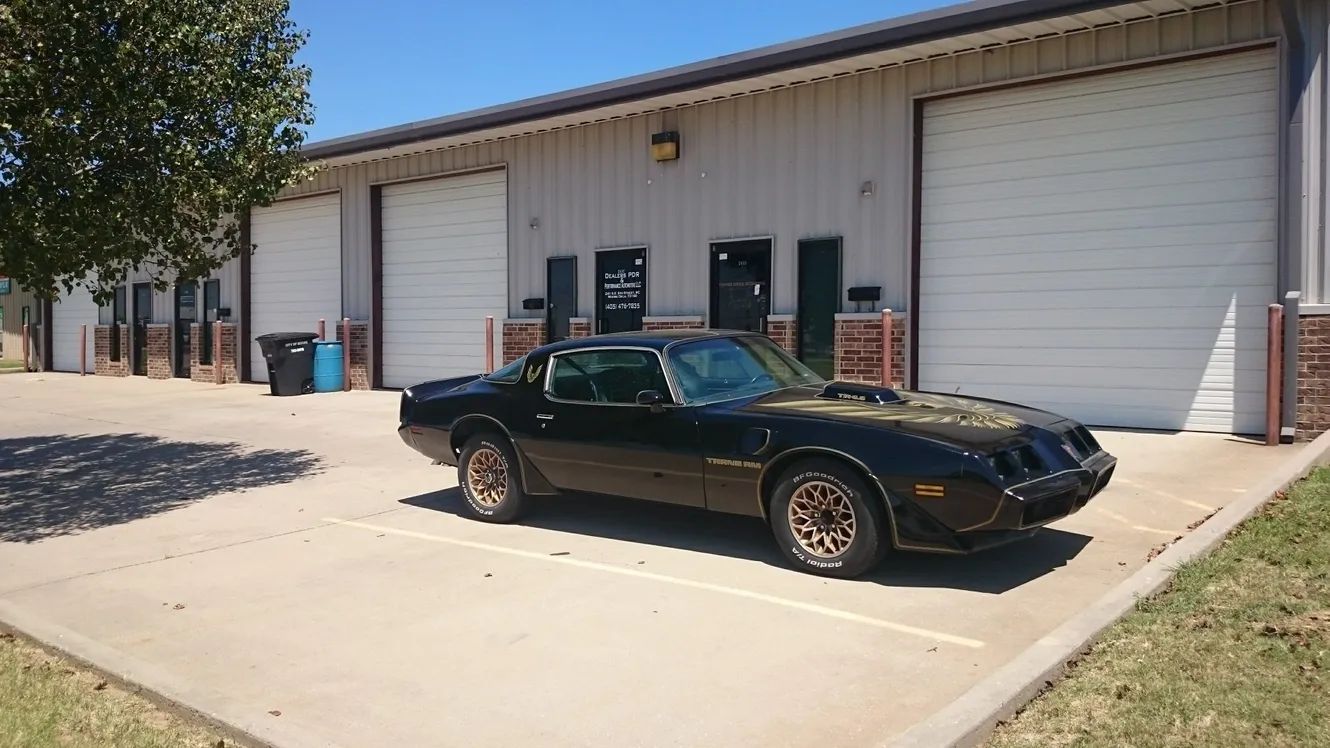 A black car is parked in front of a garage.