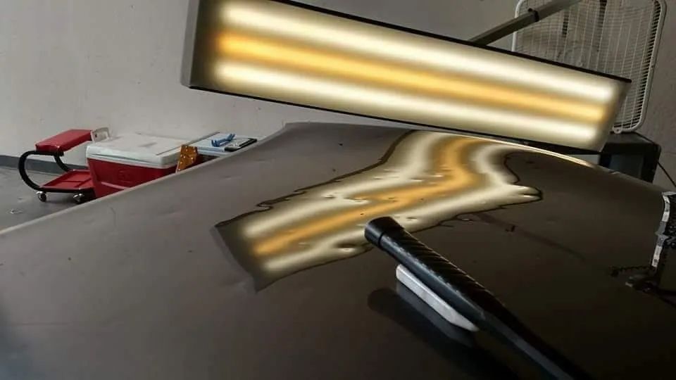 A light is shining on a damaged car hood.