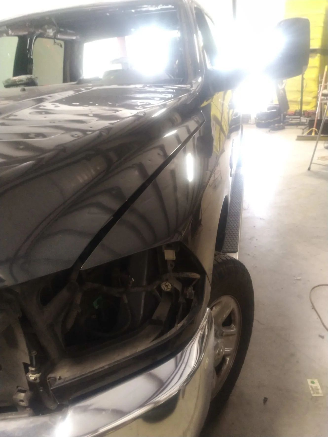 A black truck with the hood up in a garage