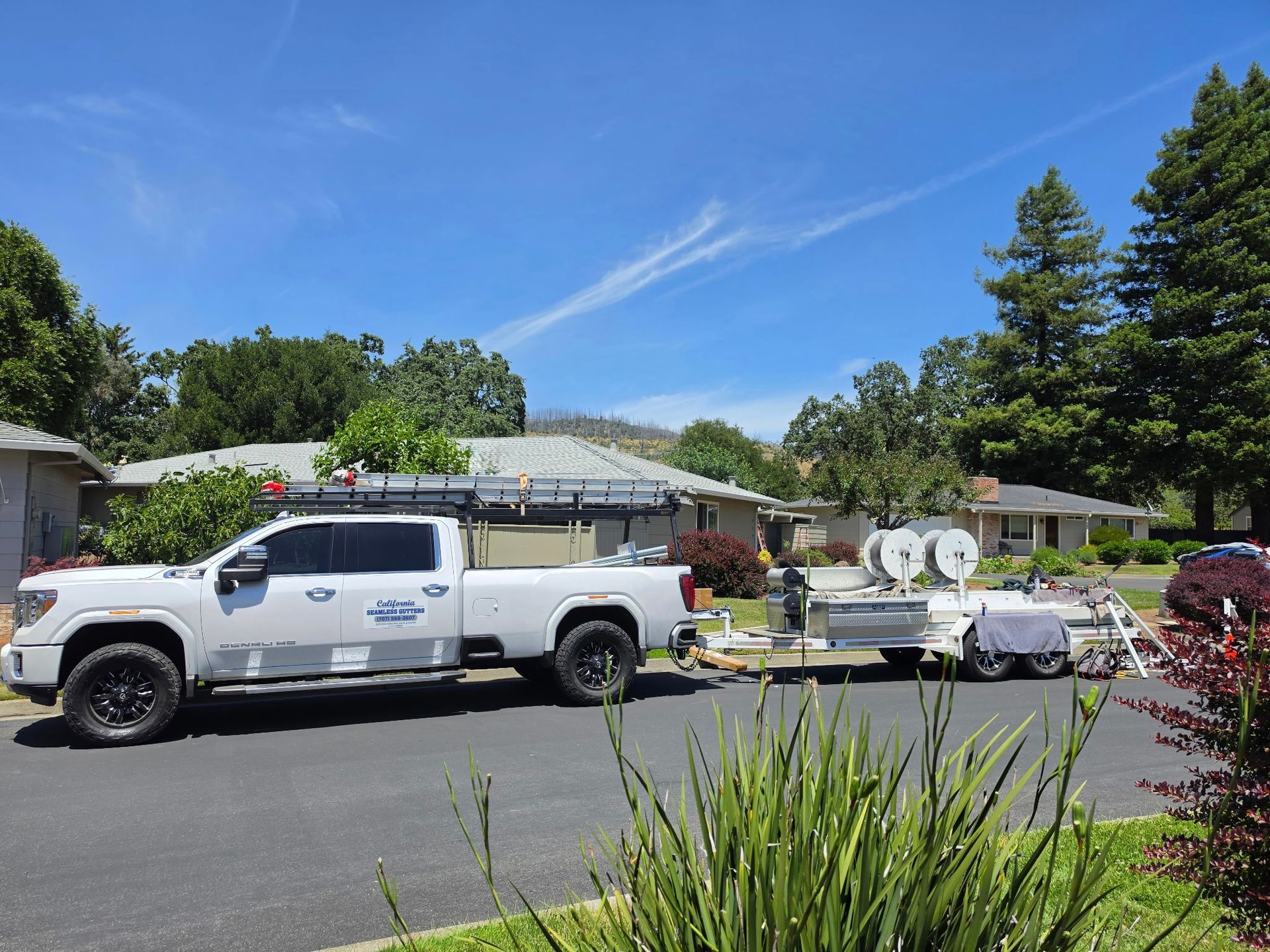 California Seamless Gutters work truck and trailer parked outside a residential home.
