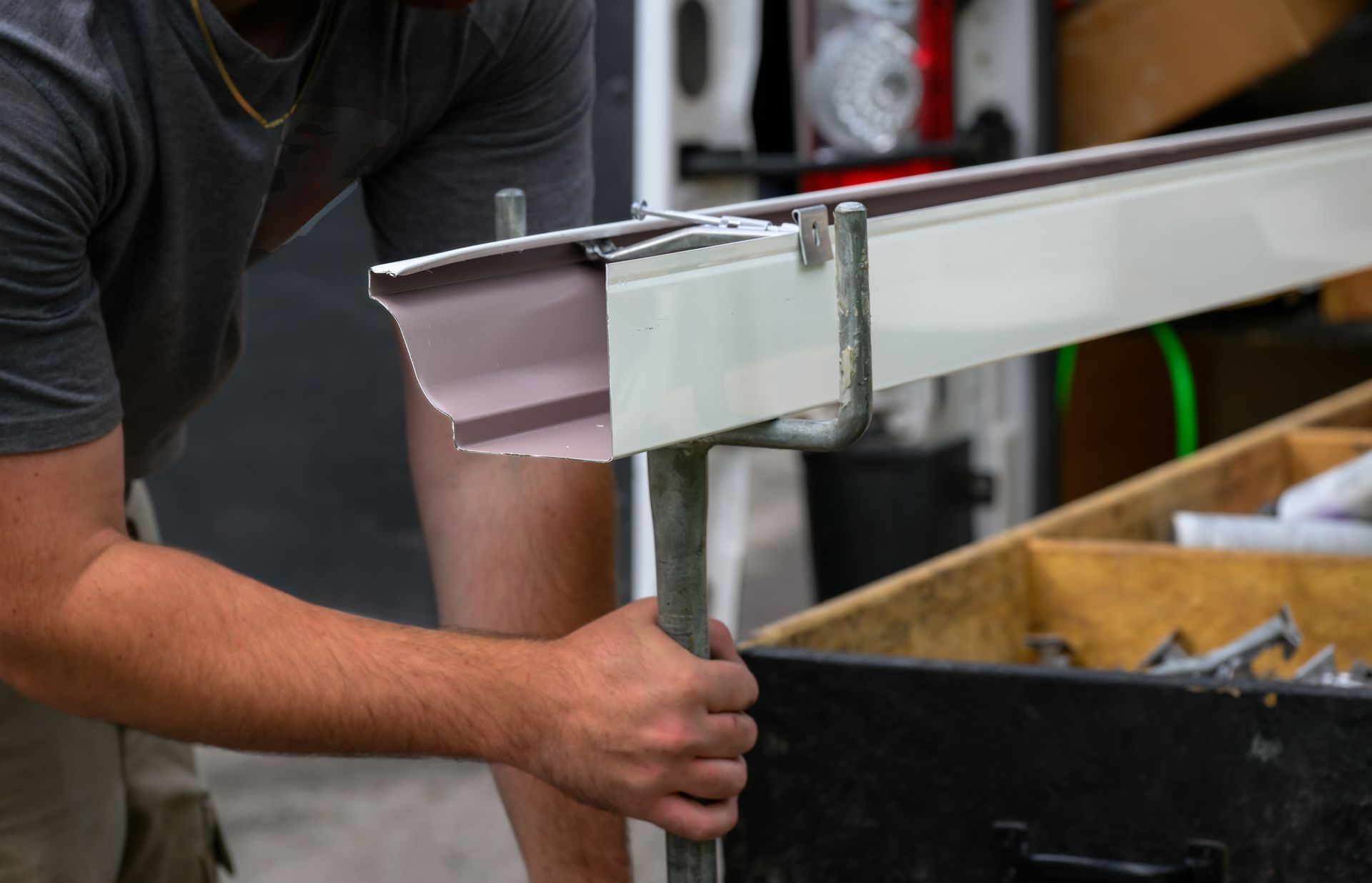 Person holding a metal frame in a workshop beside a workbench
