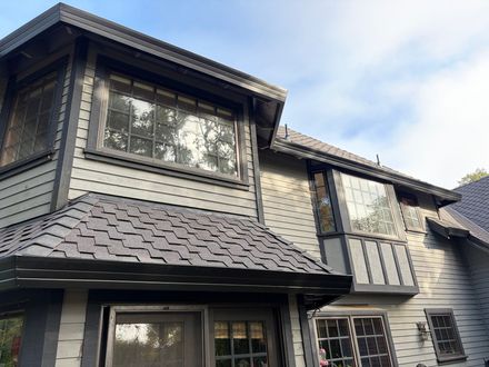 Two-story home with black gutters and a shingle roof. Two-story home with black gutters and a shingle roof.