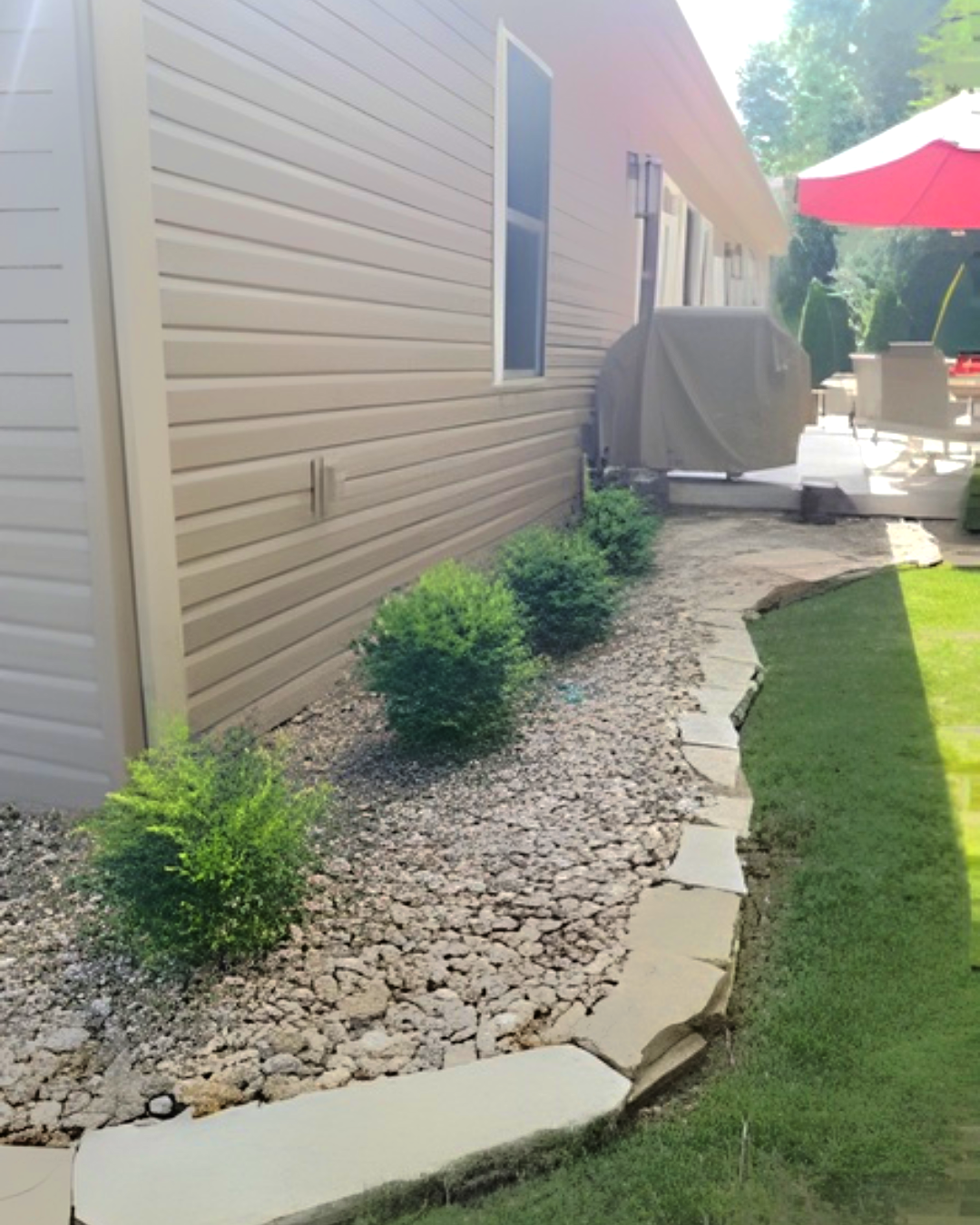 Stone walkway bordered by landscaping and retaining walls, leading to a garden.