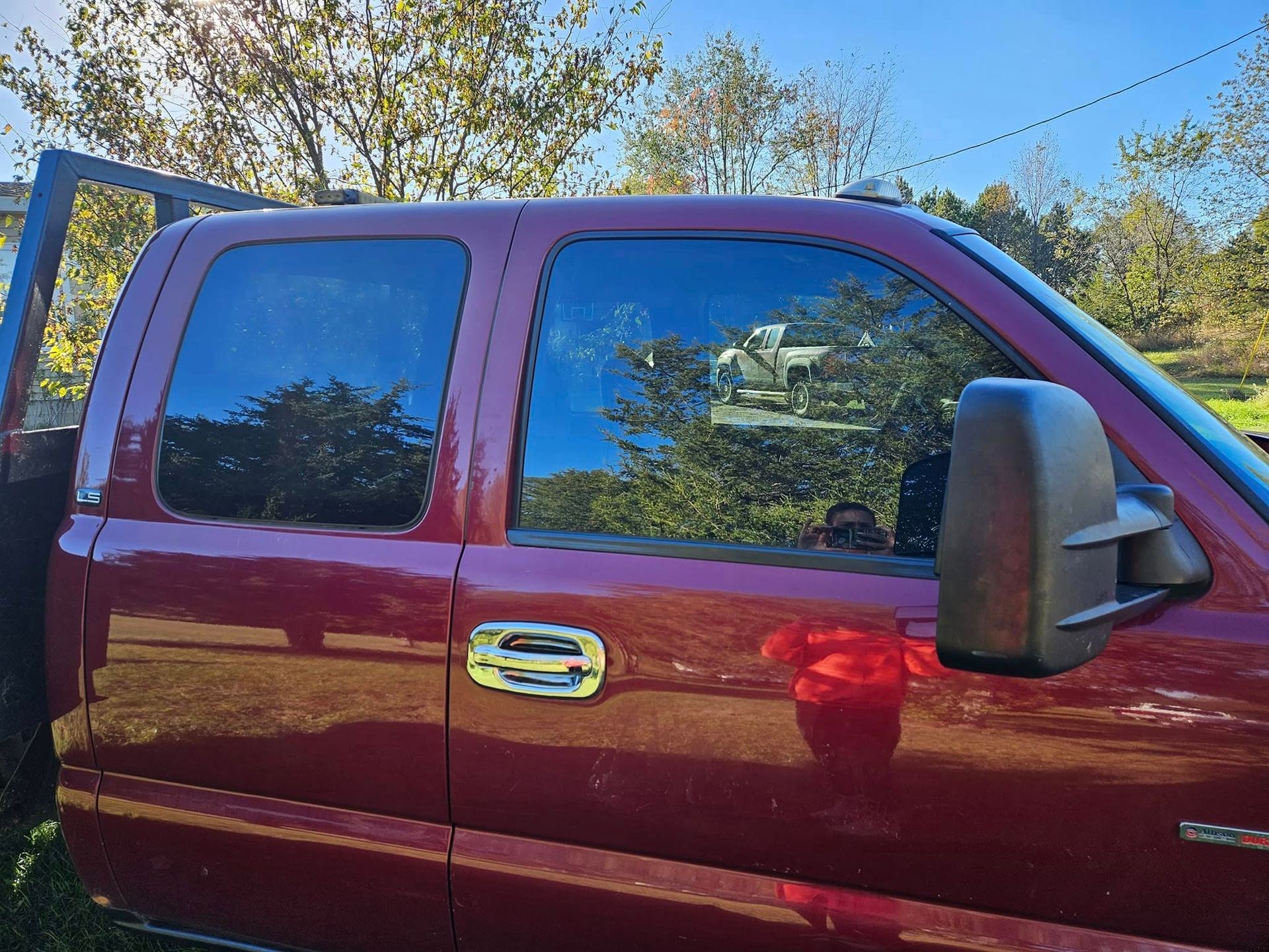 Red pickup truck with tinted windows, outdoors on a sunny day.