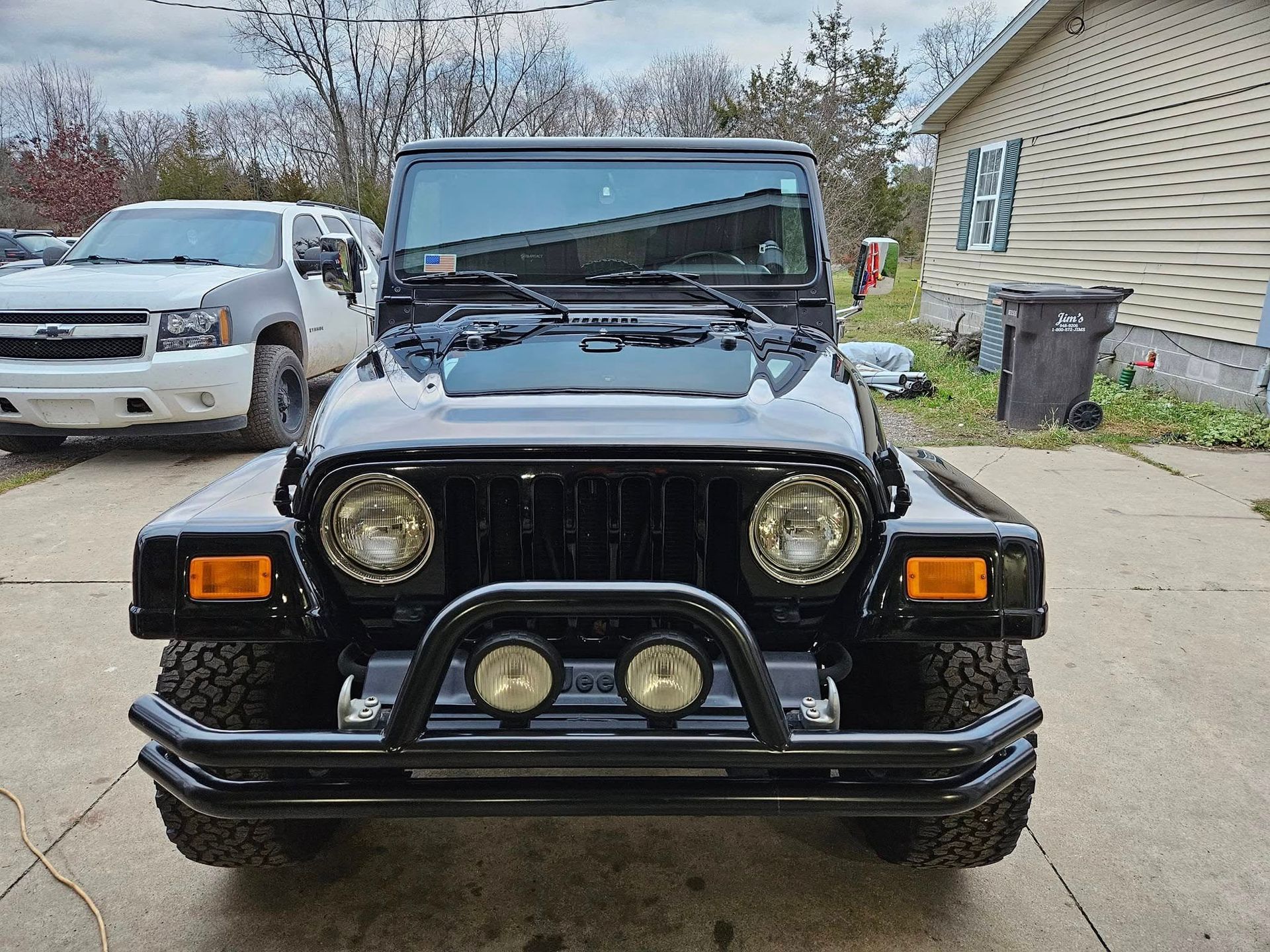 Black Jeep Wrangler with a front brush guard and auxiliary lights parked outdoors.