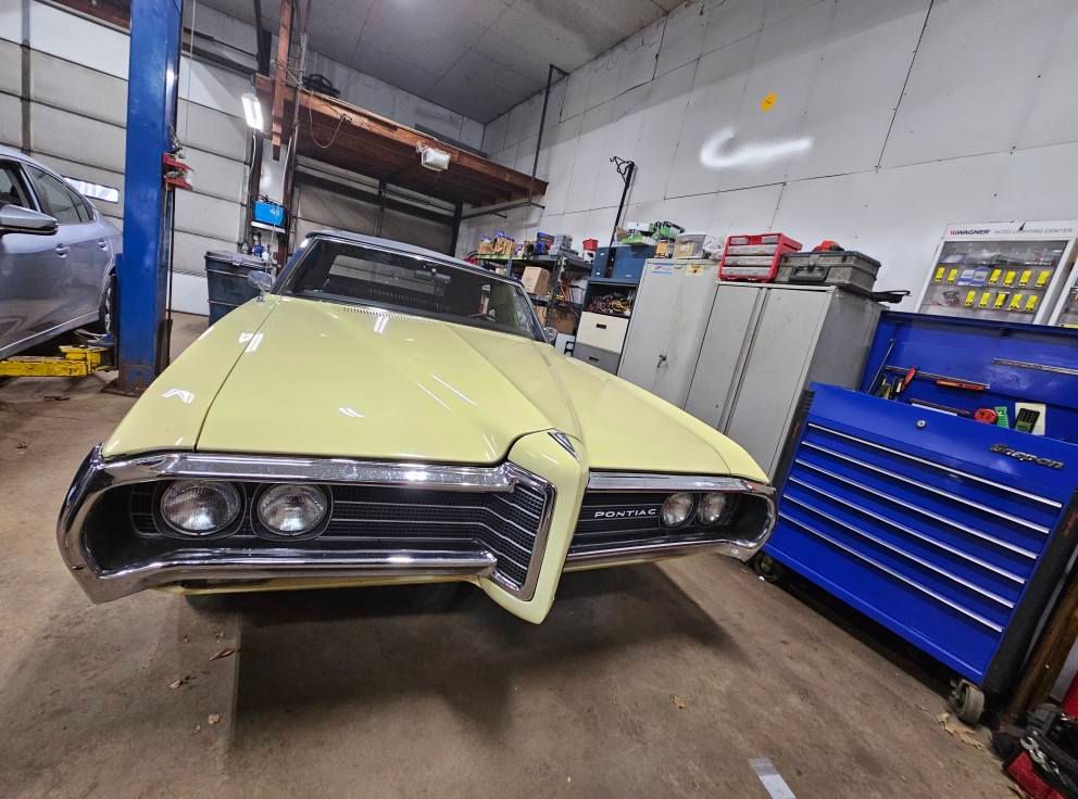 Yellow classic Pontiac in a garage, facing the viewer.
