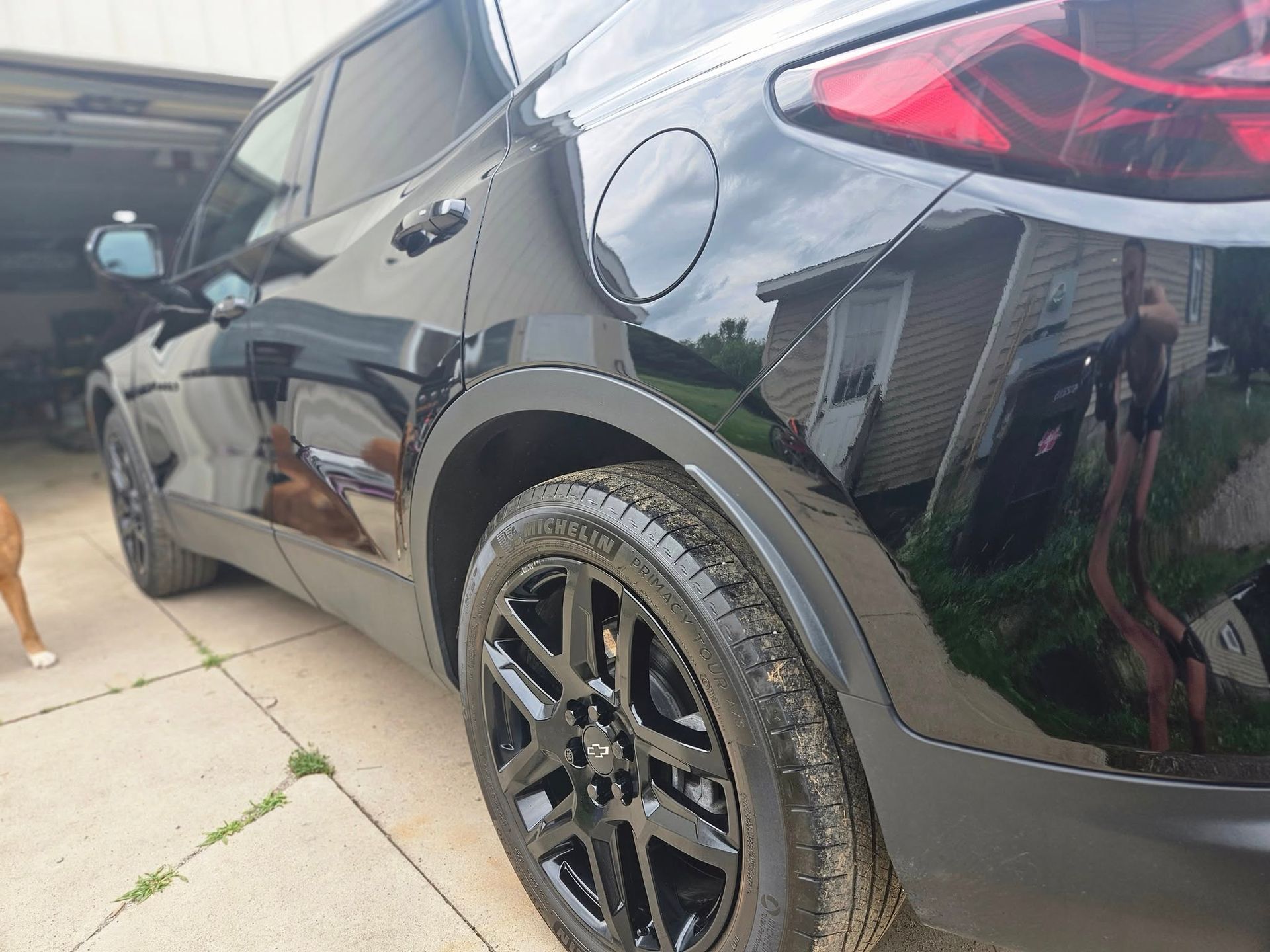 Black SUV parked on a concrete driveway; black rims, tinted windows, in front of a garage.