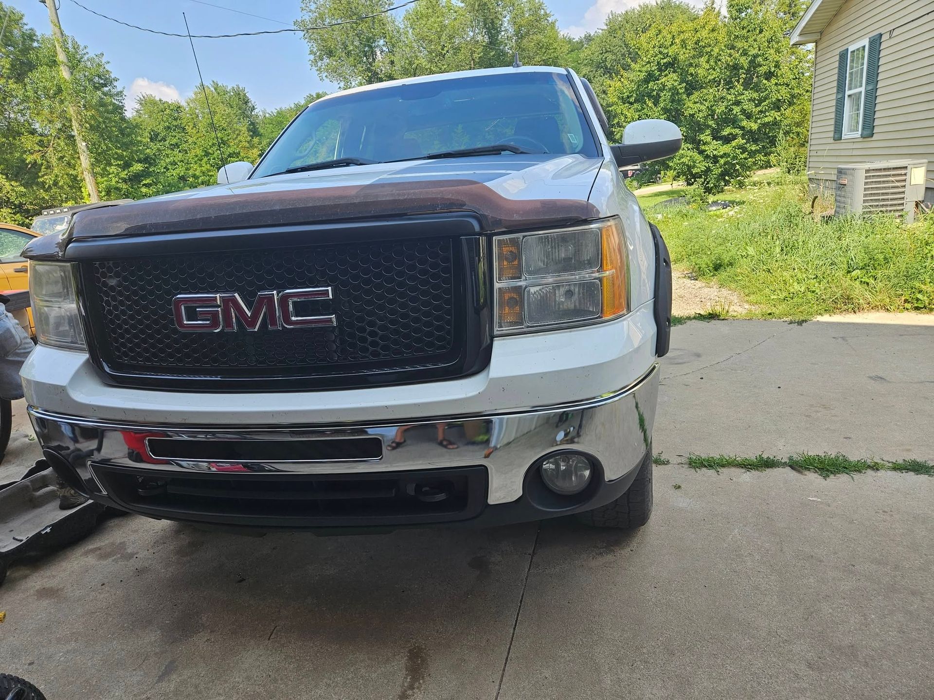 White GMC Sierra truck with a black grille and chrome bumper.