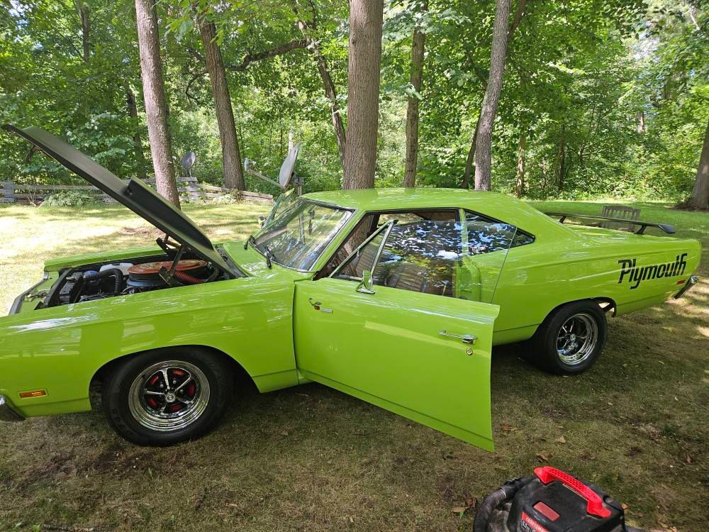 Bright green 1969 Plymouth Road Runner with open hood and door parked outdoors. 