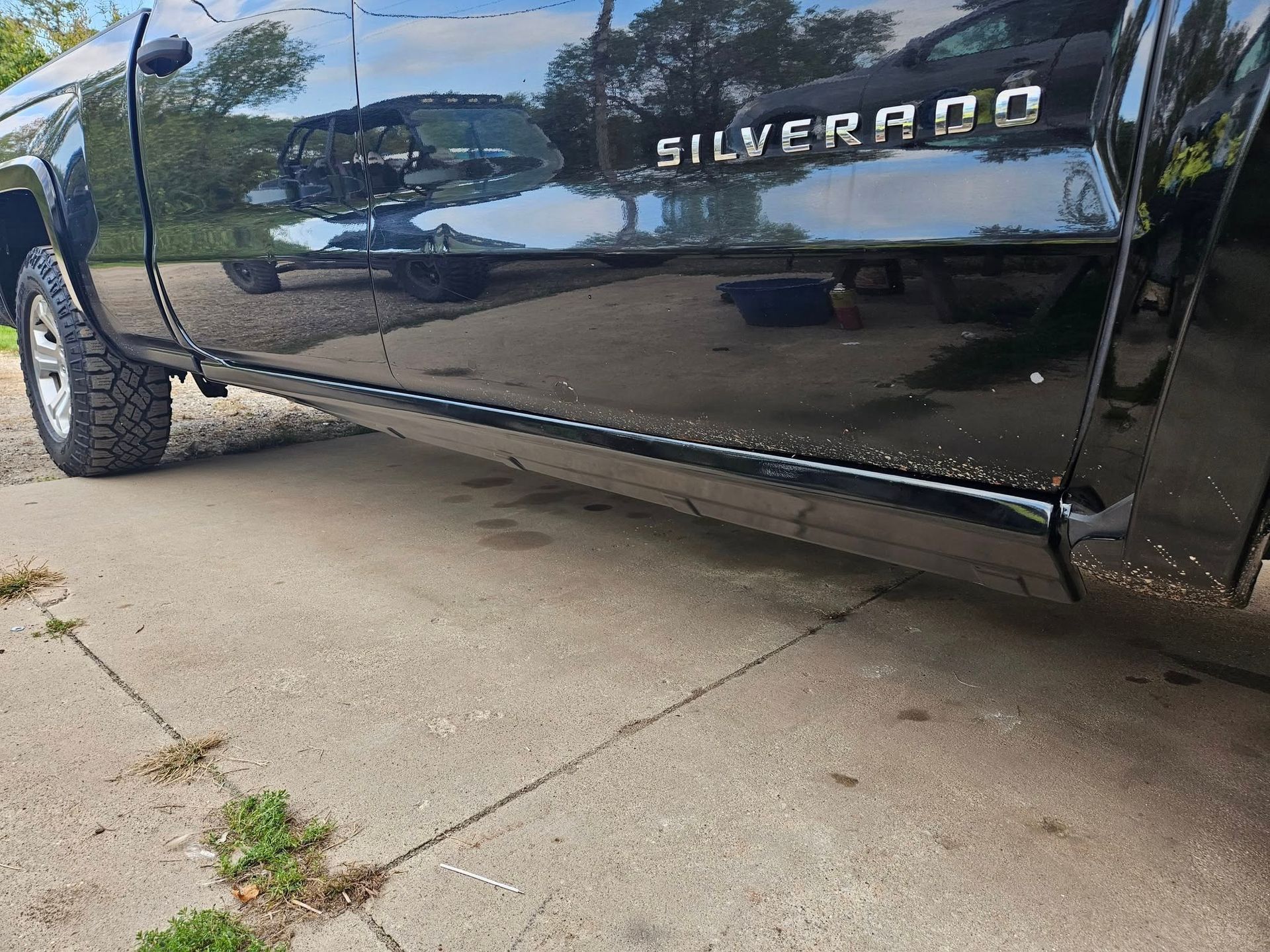 Black Chevrolet Silverado truck parked on concrete. Side view shows 