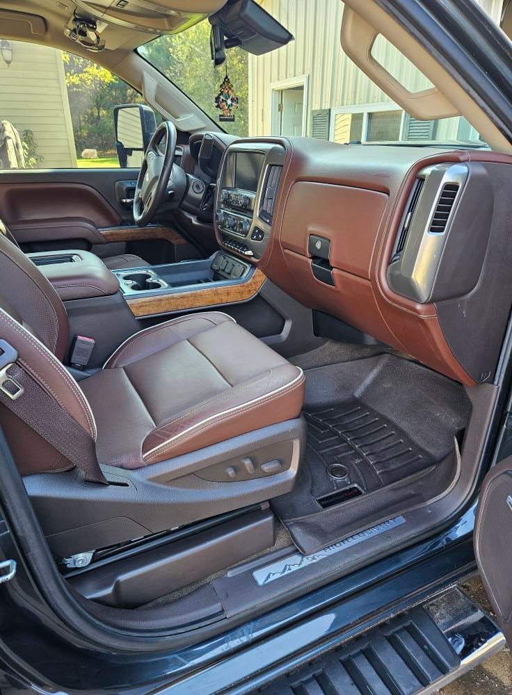 Interior view of a brown leather truck cab with a black dashboard and floor mats.