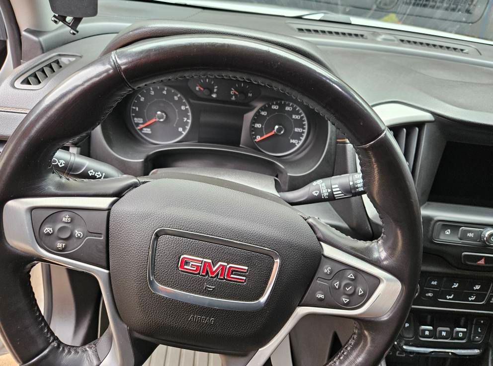 Interior view of a GMC vehicle's steering wheel and dashboard, with gauges and controls visible.