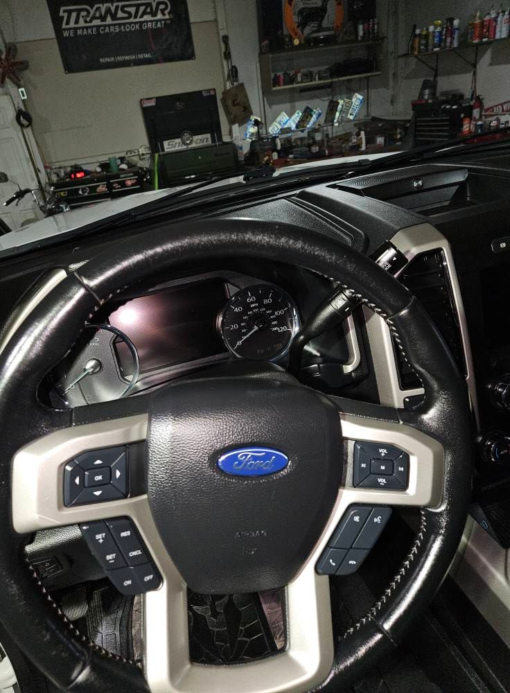 Ford truck steering wheel with controls and dashboard visible.