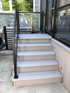 Un ensemble d'escaliers menant à un porche grillagé avec une balustrade en verre.