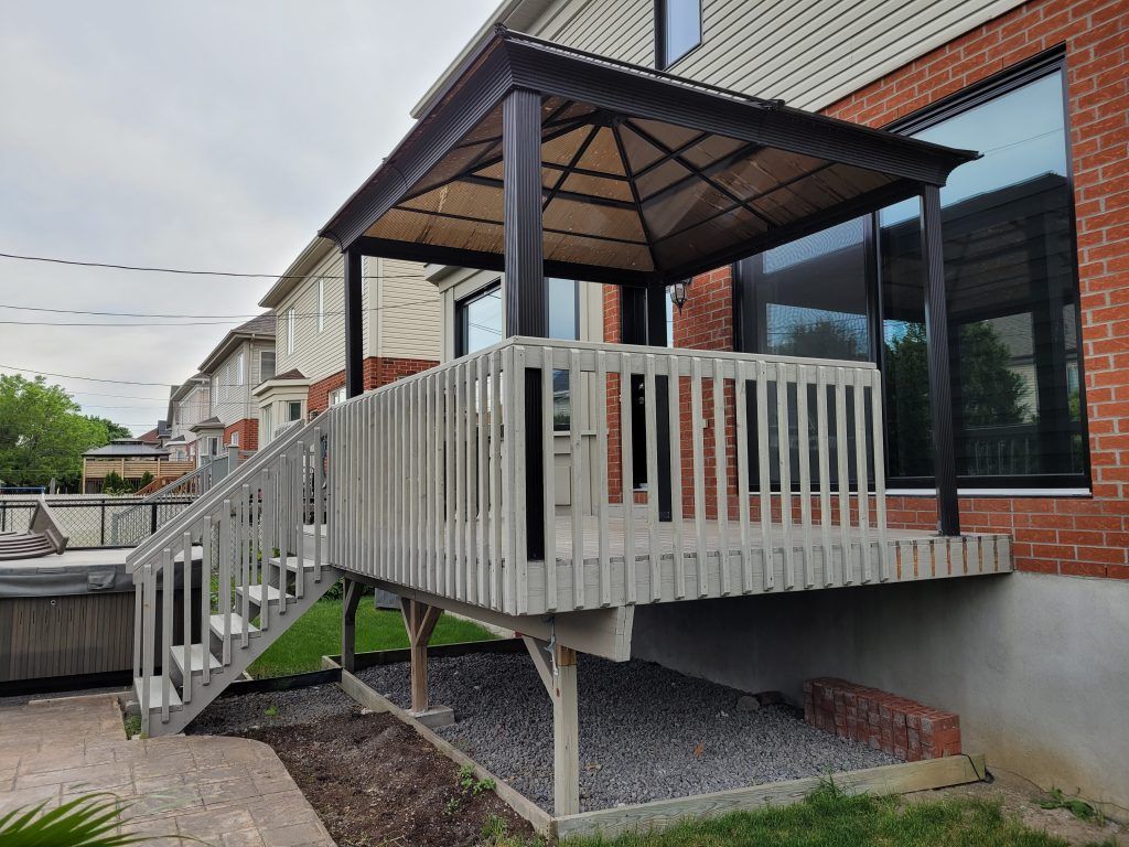 Une terrasse avec des escaliers et un gazebo dans l'arrière-cour d'une maison.