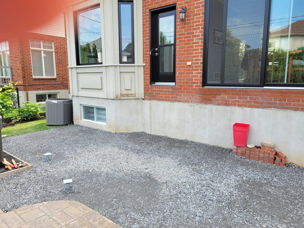 Une maison en briques avec un seau rouge devant