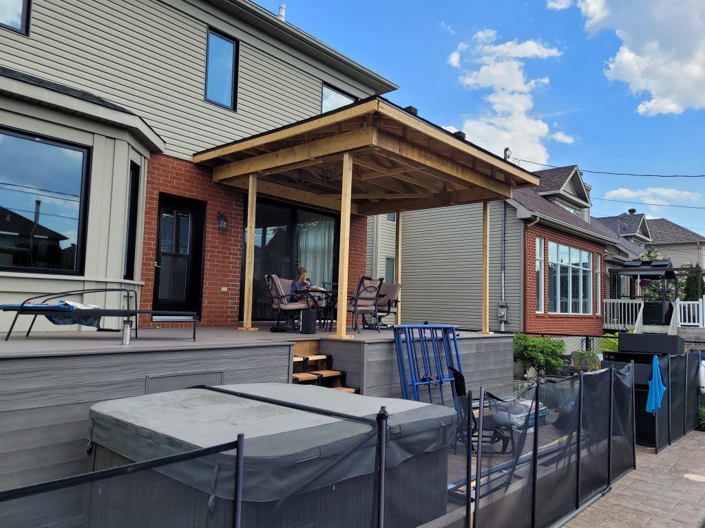 Une grande maison avec une grande terrasse et une clôture autour.