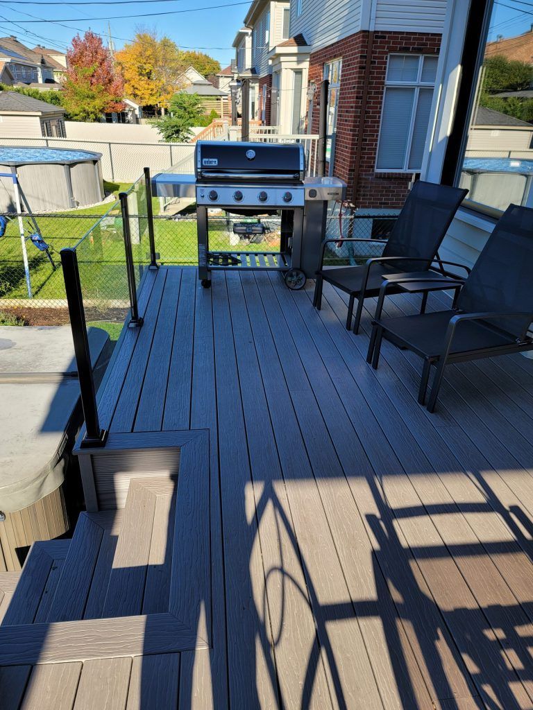 Une terrasse en bois avec un barbecue et des chaises dessus.