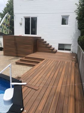 Une terrasse en bois avec des escaliers menant à côté d'une piscine.