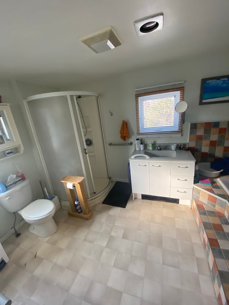 Une salle de bain avec WC, lavabo, douche et fenêtre.