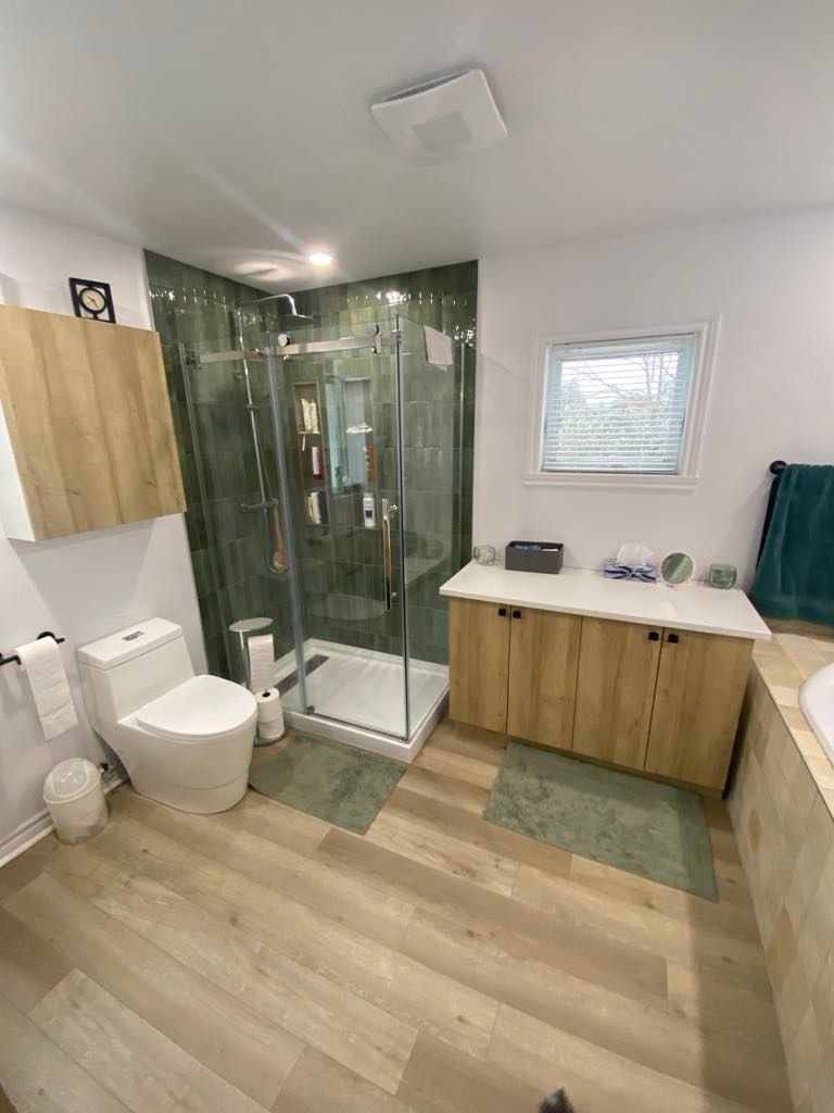 Une salle de bain avec WC, lavabo, douche et fenêtre.