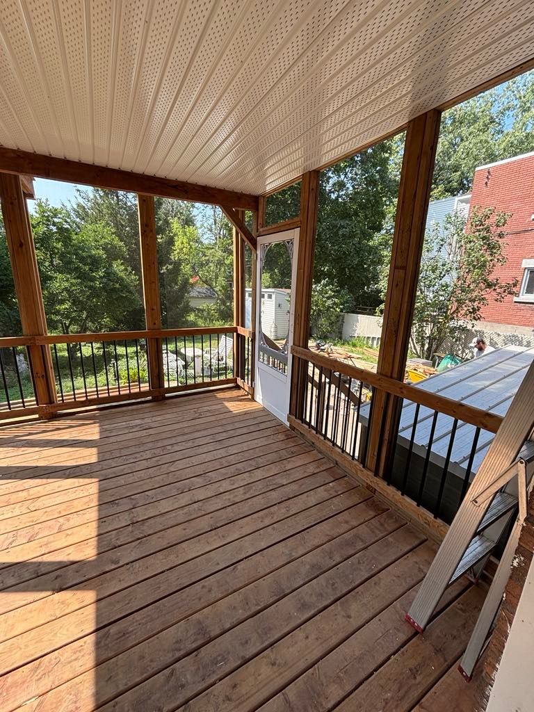 Un porche grillagé avec une terrasse en bois et une échelle.